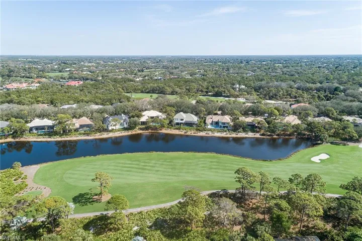 Aerial view of residential area featuring a golf course and a nearby body of water