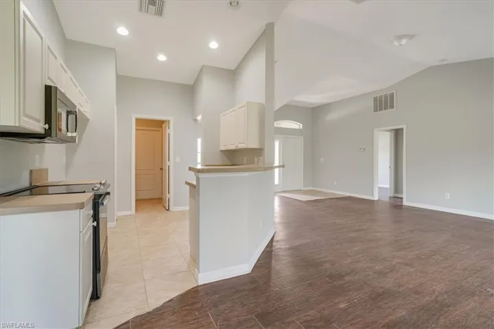 Kitchen featuring light wood-type flooring, white cabinetry, kitchen peninsula, and range with electric stovetop