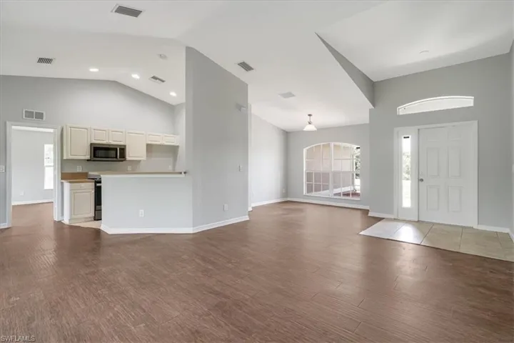 Unfurnished living room featuring high vaulted ceiling and hardwood / wood-style flooring