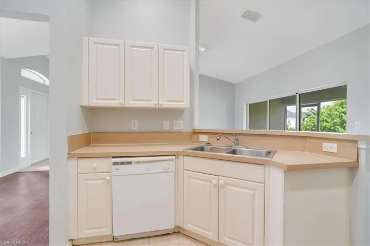 Kitchen featuring lofted ceiling, sink, white cabinetry, dishwasher, and light hardwood / wood-style floors