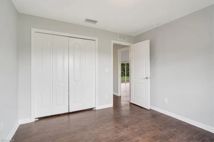 Unfurnished bedroom with dark hardwood / wood-style floors and a closet