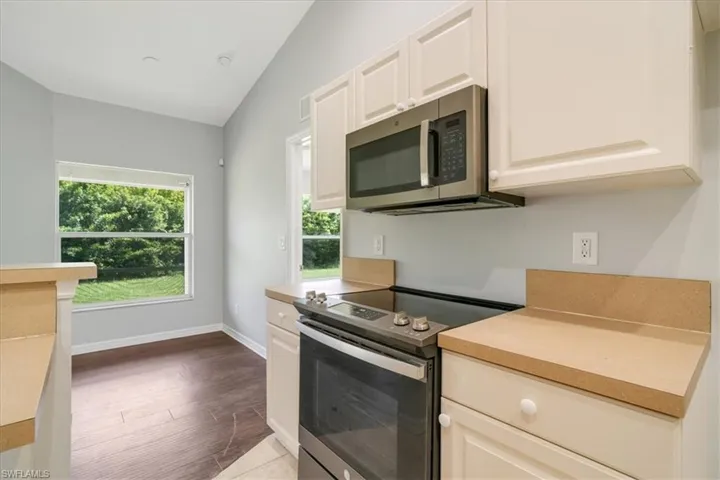 Kitchen with stainless steel appliances, hardwood / wood-style floors, and lofted ceiling