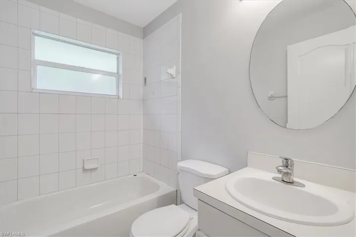 Full bathroom with tiled shower / bath, vanity, and toilet