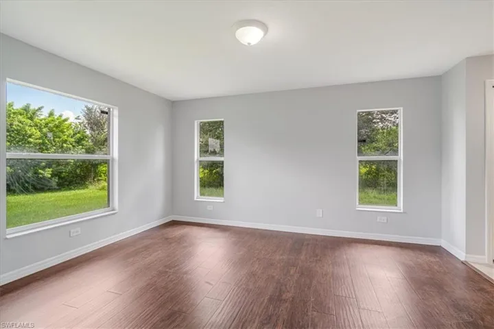 Spare room featuring dark hardwood / wood-style floors and a healthy amount of sunlight