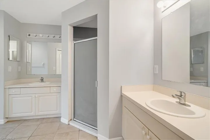 Bathroom with walk in shower, tile patterned flooring, and vanity