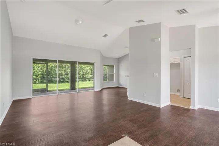 Empty room with lofted ceiling and dark hardwood / wood-style floors