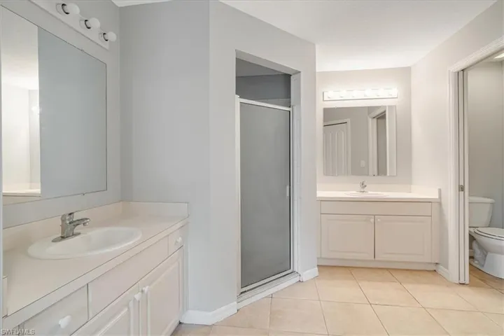 Bathroom with tile patterned floors, an enclosed shower, vanity, and toilet