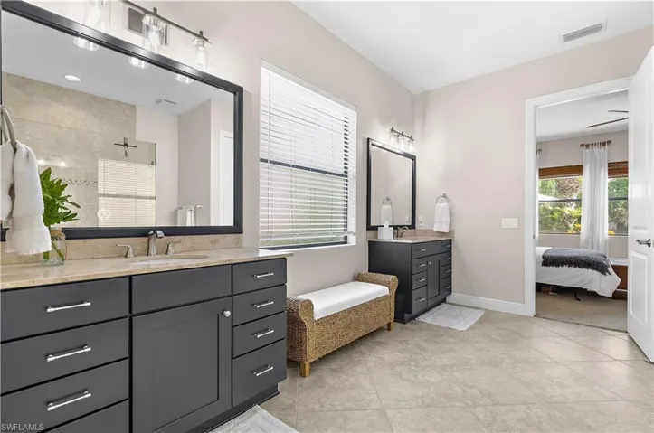 Dual vanity bathroom featuring dark wood cabinetry, light-toned stone countertops, and rectangular framed mirrors