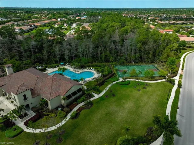 Mediterranean-style clubhouse with a terracotta tile roof, featuring a resort-style swimming pool, surrounding lounge area, and a dedicated sports court