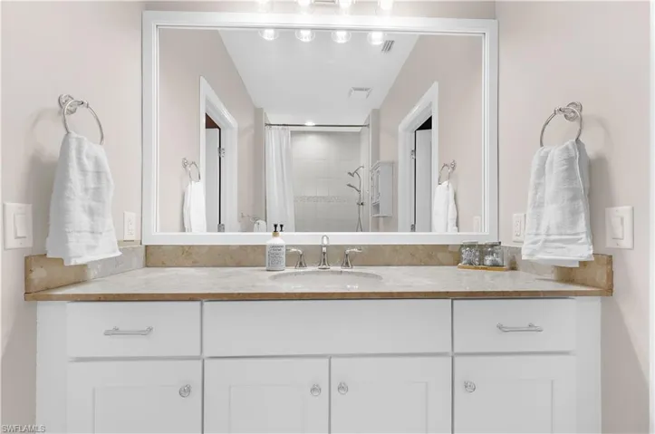White vanity with polished chrome hardware, an integrated sink, and a light-toned stone countertop