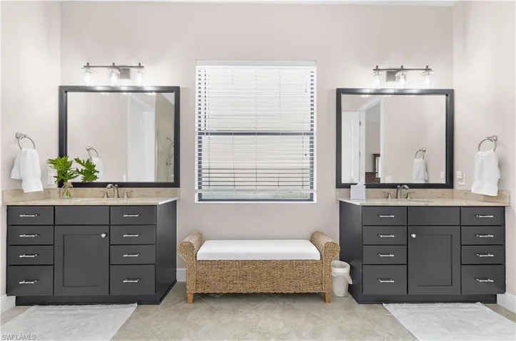 Dual vanity setup featuring dark cabinetry with brushed nickel hardware, stone countertops, and rectangular framed mirrors