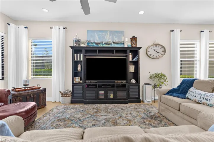 Spacious living area featuring light-toned walls, recessed lighting, and wood-finish flooring