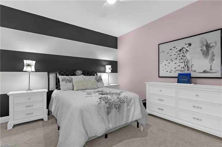 Room featuring a striped accent wall, light pink wall, and neutral carpet flooring