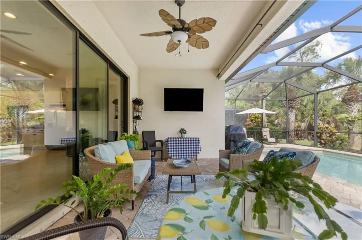 Covered patio featuring a ceiling fan, a wall-mounted television, and a screened enclosure