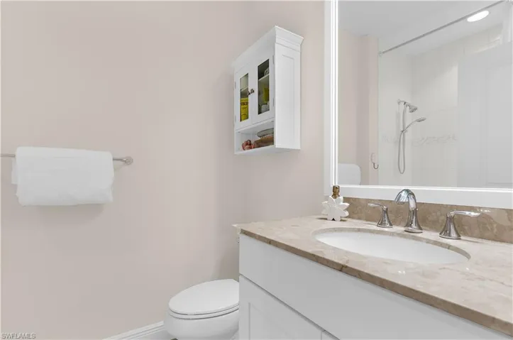 Bathroom featuring a vanity with an integrated sink and stone countertop, chrome faucet, and a wall-mounted mirror