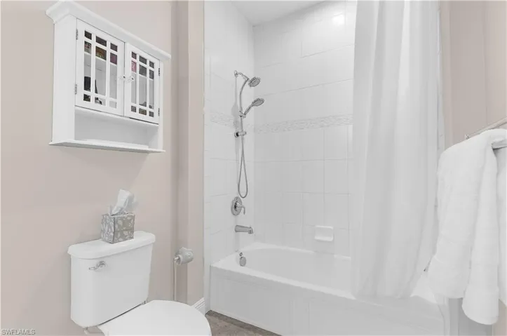 Tub and shower combination featuring white subway tile surround with decorative accent band