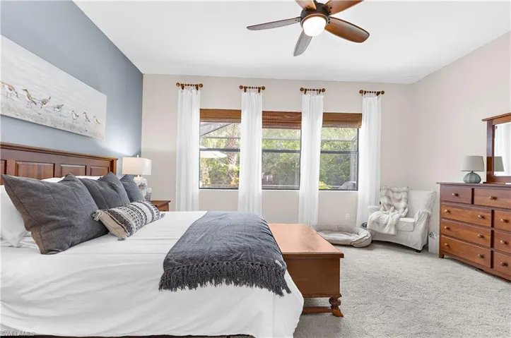Carpeted room featuring a ceiling fan with integrated lighting, three windows with natural light, and a two-tone wall finish