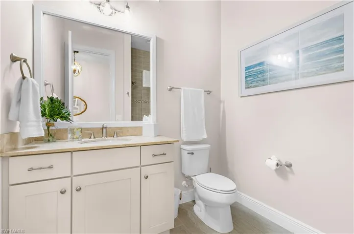Bathroom featuring a single vanity with a light-toned countertop, shaker-style cabinetry, and a framed mirror