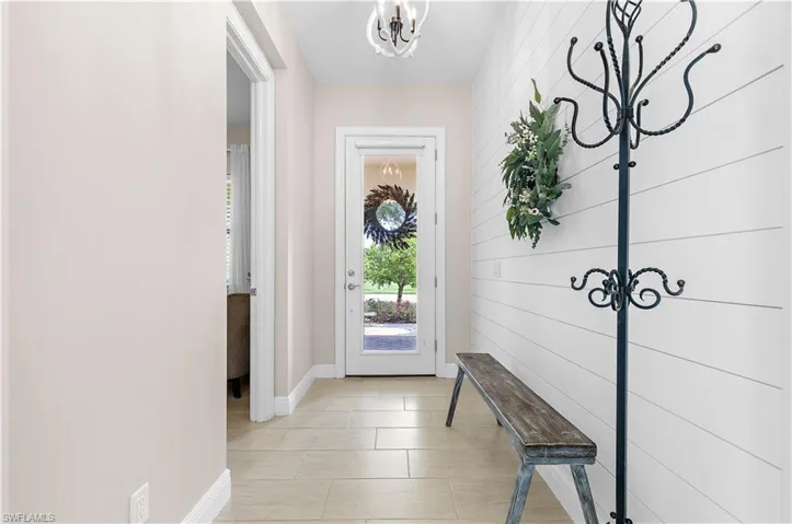 Entryway featuring light-toned tile flooring, white shiplap wall accent, and a full-light entry door