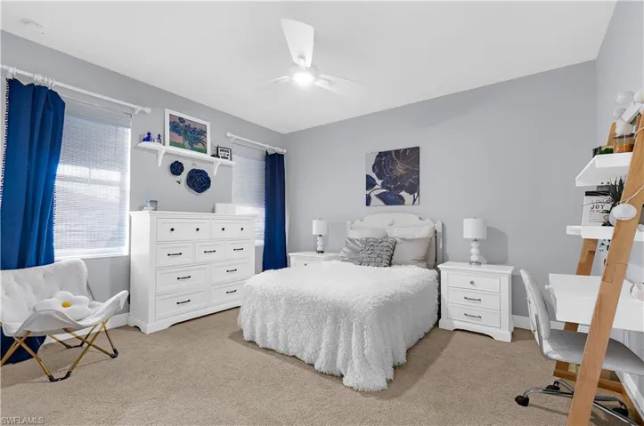 Carpeted room featuring light gray walls, a white ceiling fan, and two windows with blinds