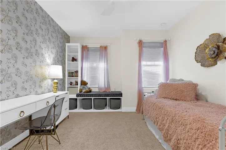 Room featuring a decorative accent wall, built-in shelving, a window with blinds, and carpeted flooring