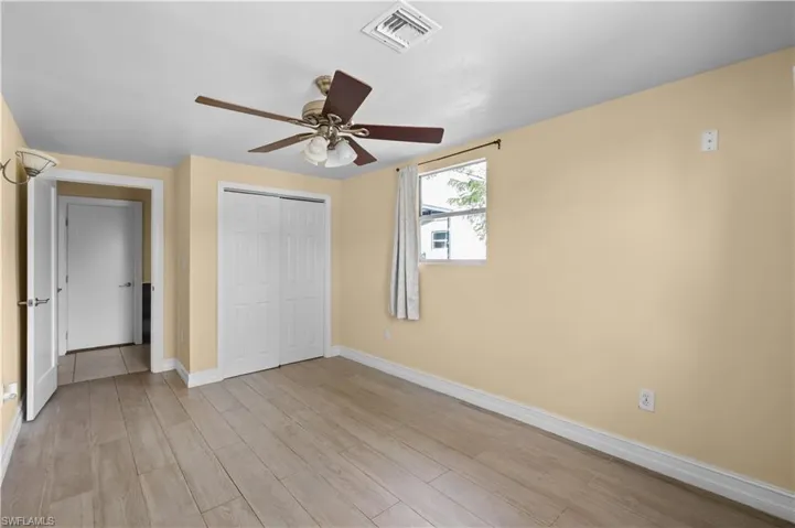 Unfurnished bedroom with light wood finished floors, a closet, and a ceiling fan