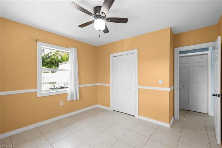 Unfurnished bedroom featuring light tile patterned flooring, a ceiling fan, and a closet