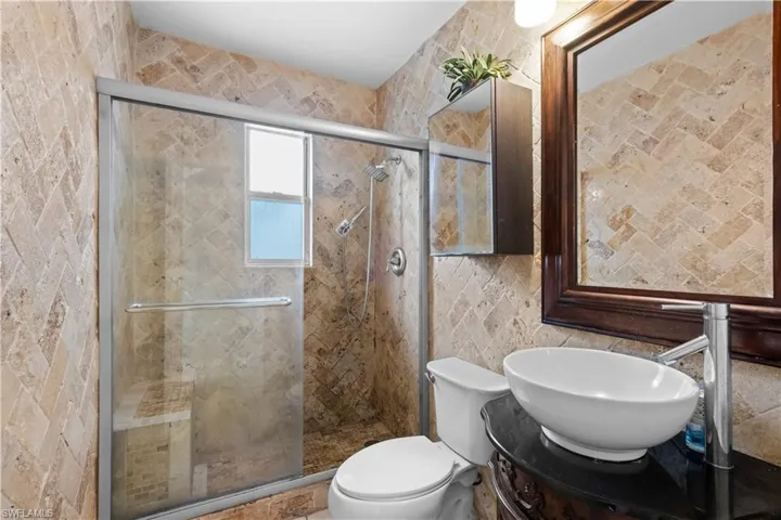 Bathroom featuring vanity, tile walls, a shower stall, and backsplash