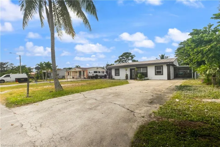 Ranch-style house with concrete driveway, a front yard, stucco siding, and a metal roof