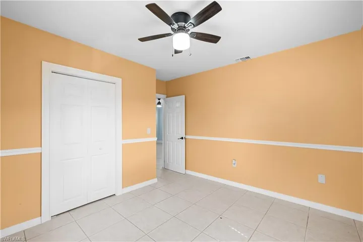Unfurnished bedroom with light tile patterned flooring, ceiling fan, and a closet