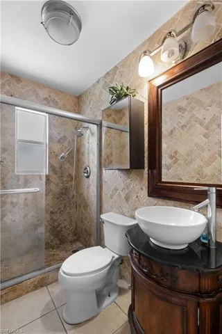 Bathroom featuring vanity, light tile patterned flooring, a shower stall, and tile walls