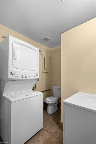 Laundry area with light tile patterned floors and estacked washer and dryer