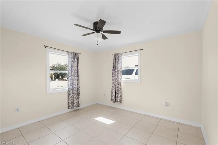 Spare room featuring healthy amount of natural light, light tile patterned floors, ornamental molding, and a ceiling fan