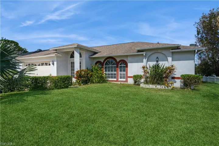 Ranch-style home featuring a front lawn and a garage