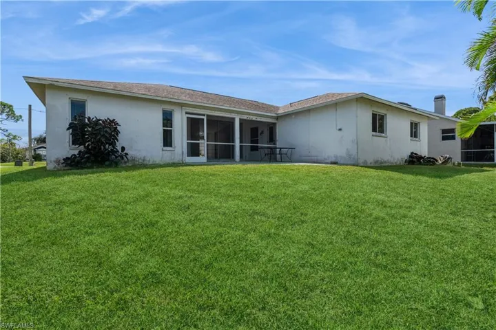 Rear view of house with a lawn and a sunroom