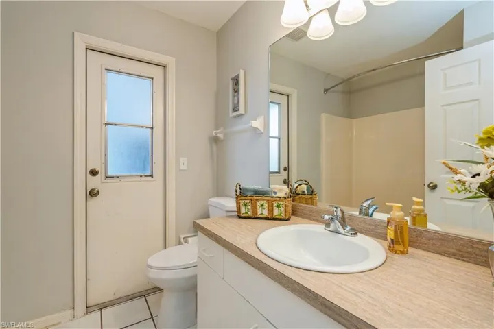 Bathroom with walk in shower, vanity, toilet, and tile patterned flooring
