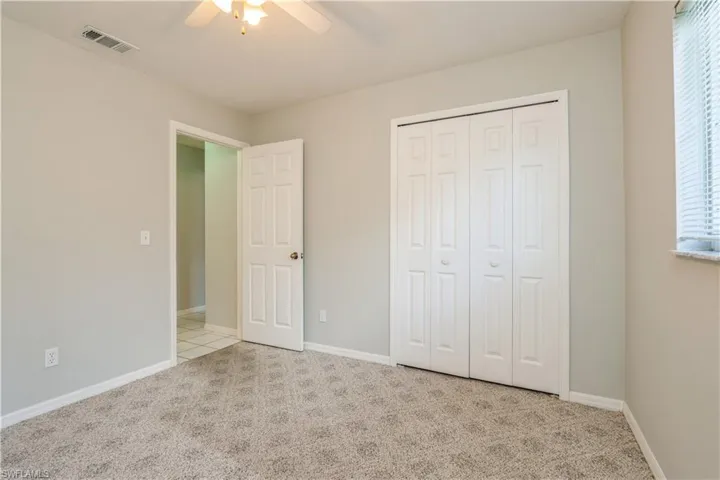 Unfurnished bedroom featuring a closet, ceiling fan, multiple windows, and light colored carpet