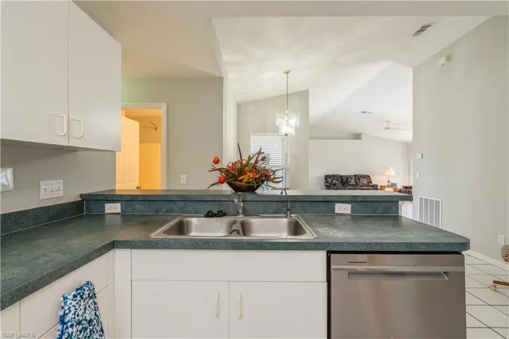 Kitchen featuring white cabinets, stainless steel dishwasher, and vaulted ceiling