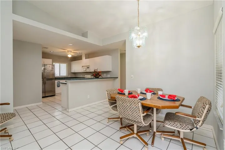 Dining area with lofted ceiling, light tile patterned flooring, and ceiling fan with notable chandelier