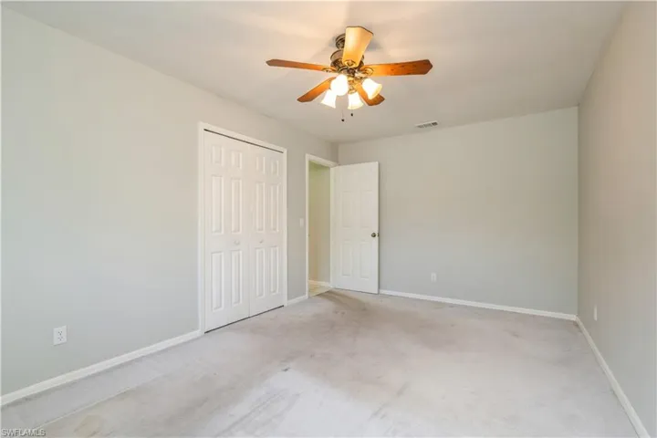 Unfurnished bedroom featuring light carpet, a closet, and ceiling fan