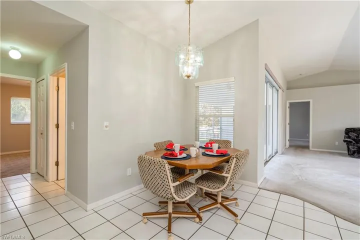Dining space featuring a notable chandelier, light colored carpet, and vaulted ceiling