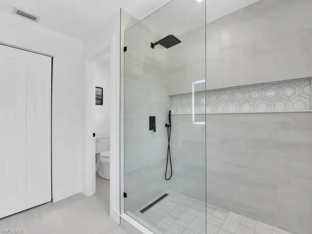 Bathroom with tile floors, a shower with door, and toilet