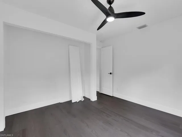 Empty room featuring ceiling fan and dark wood-type flooring