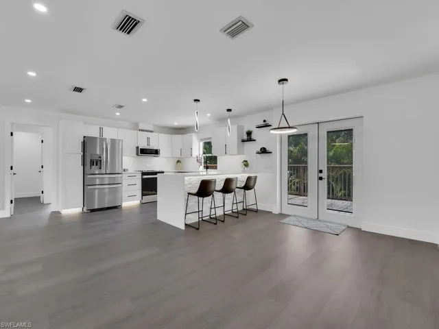 Kitchen featuring stainless steel appliances, dark wood-type flooring, white cabinetry, and tasteful backsplash