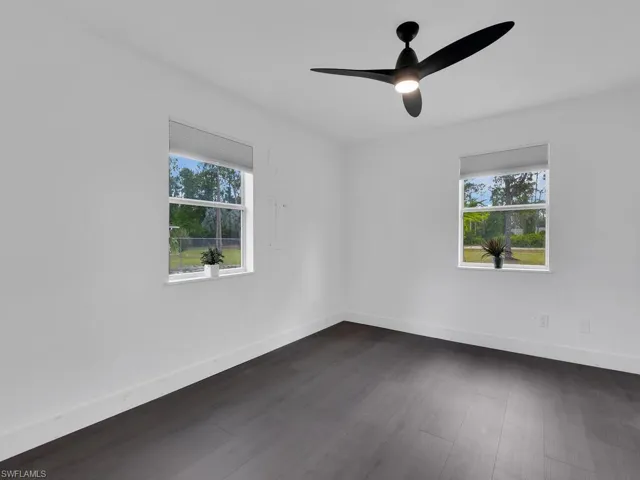 Spare room with a healthy amount of sunlight, dark wood-type flooring, and ceiling fan