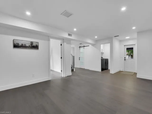 Unfurnished living room with dark hardwood / wood-style flooring and a barn door