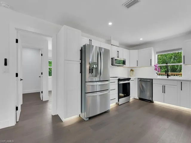 Kitchen with stainless steel appliances, dark hardwood / wood-style flooring, and tasteful backsplash
