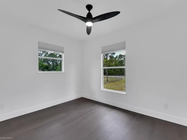 Unfurnished room featuring ceiling fan and dark wood-type flooring