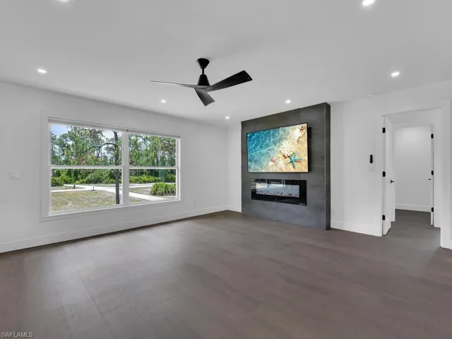 Unfurnished living room featuring ceiling fan, dark hardwood / wood-style flooring, and a large fireplace