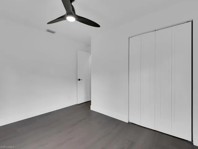 Unfurnished bedroom featuring dark hardwood / wood-style flooring, a closet, and ceiling fan